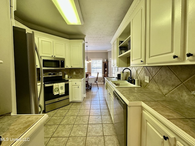 kitchen with sink, crown molding, tile countertops, hanging light fixtures, and stainless steel appliances