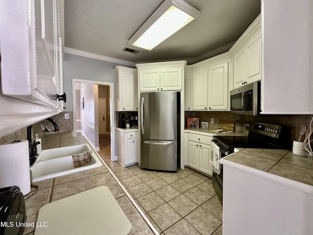 kitchen featuring stainless steel appliances, white cabinetry, and backsplash