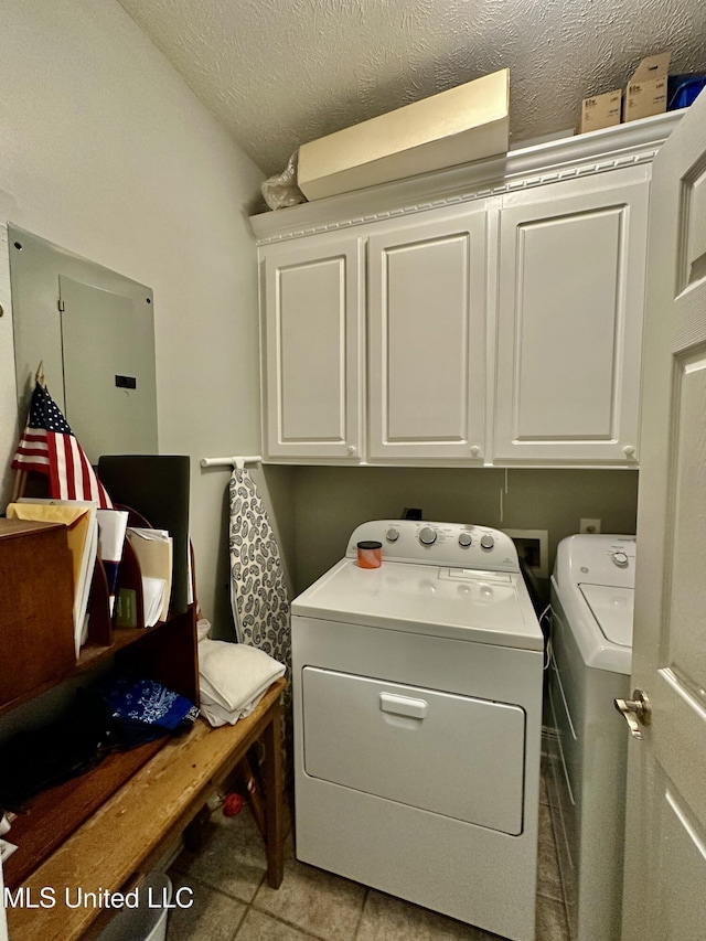 laundry area with a textured ceiling, cabinets, and washing machine and clothes dryer