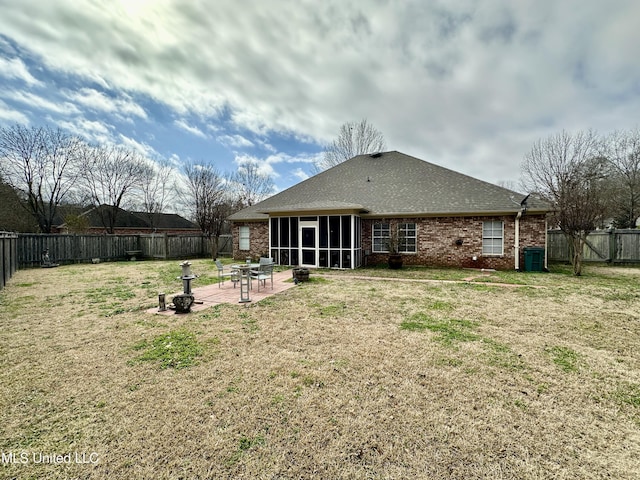 rear view of property featuring a lawn, a sunroom, and a patio