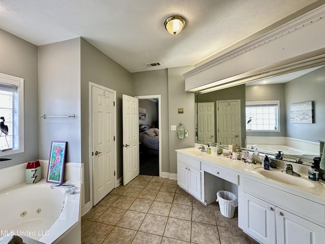 bathroom with tile patterned floors, vanity, a bath, and a textured ceiling