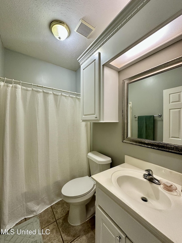 bathroom with tile patterned floors, vanity, toilet, and a textured ceiling