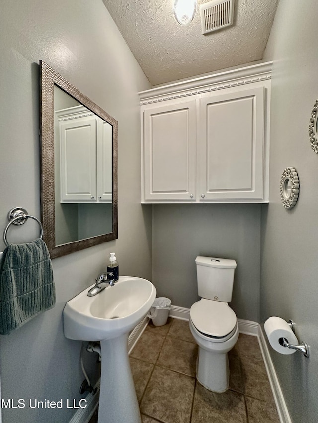 bathroom with a textured ceiling, tile patterned floors, and toilet