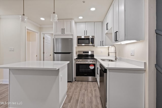 kitchen featuring appliances with stainless steel finishes, light wood-type flooring, white cabinets, and a sink