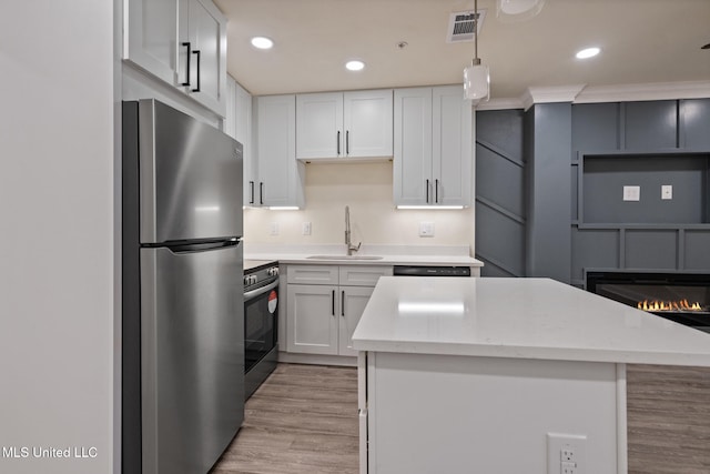 kitchen with appliances with stainless steel finishes, white cabinets, a sink, and a kitchen island