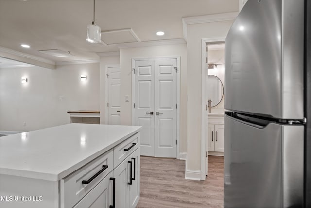 kitchen featuring white cabinetry, light wood-style floors, ornamental molding, freestanding refrigerator, and pendant lighting