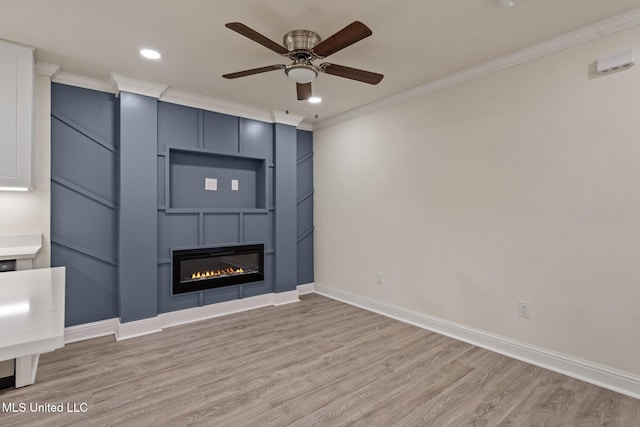 unfurnished living room with light wood finished floors, a fireplace, baseboards, and crown molding