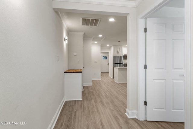 corridor featuring light wood finished floors, baseboards, visible vents, crown molding, and recessed lighting