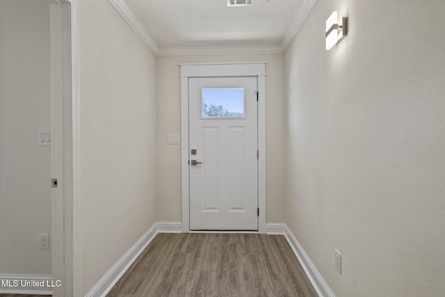 doorway with crown molding, wood finished floors, visible vents, and baseboards