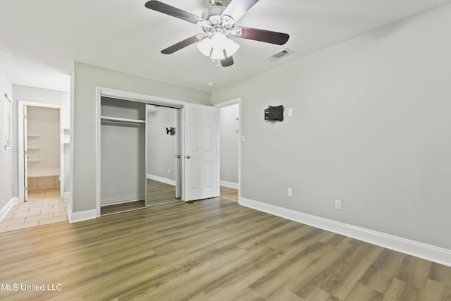 2607 Calle De Feliz St, Gautier, MS 39553 - unfurnished bedroom featuring a closet, connected bathroom, light wood-style flooring, and ceiling fan