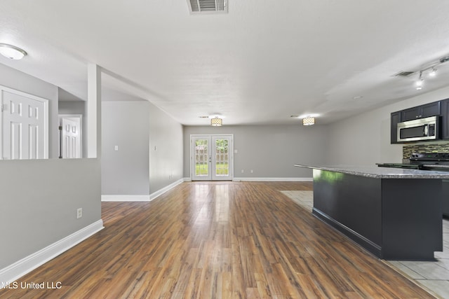 2607 Calle De Feliz St, Gautier, MS 39553 - kitchen featuring stainless steel microwave, wood finished floors, open floor plan, a kitchen island, and backsplash