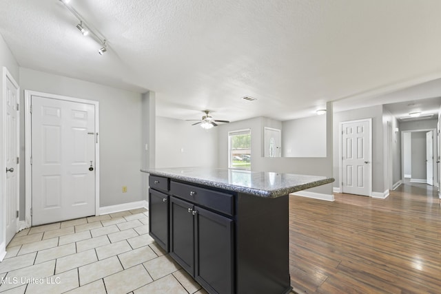 2607 Calle De Feliz St, Gautier, MS 39553 - kitchen featuring ceiling fan, a textured ceiling, a kitchen island, light wood-style floors, and light stone countertops