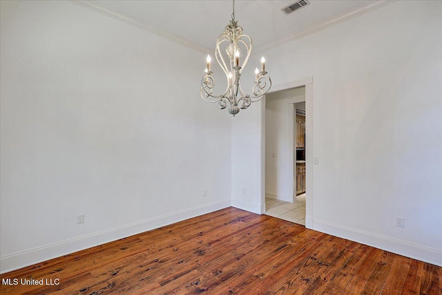 empty room with crown molding, an inviting chandelier, and light wood-type flooring