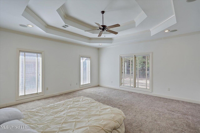 carpeted bedroom with multiple windows, ornamental molding, ceiling fan, and a tray ceiling