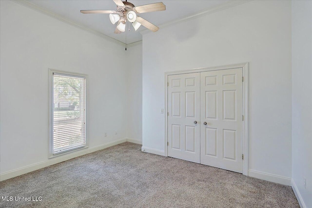 unfurnished bedroom featuring ornamental molding, light colored carpet, ceiling fan, and a closet