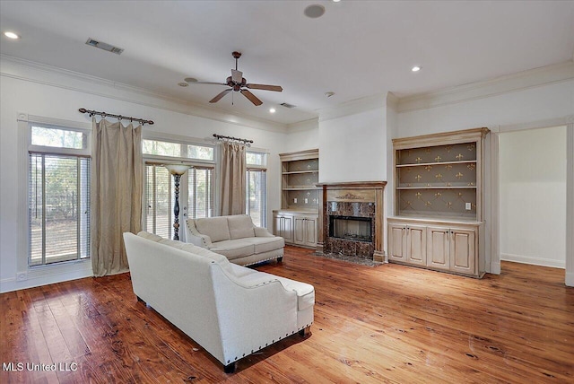 living room with hardwood / wood-style flooring, ceiling fan, a fireplace, and crown molding