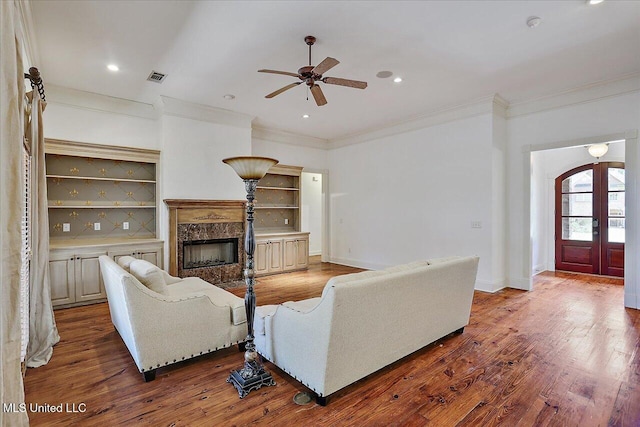 living room with a high end fireplace, ornamental molding, french doors, and wood-type flooring