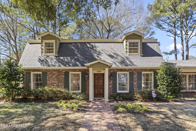 view of front of house featuring roof with shingles and brick siding