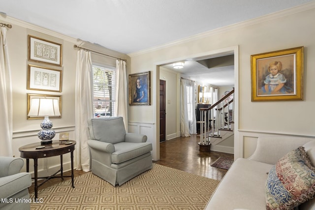 sitting room with a wainscoted wall, crown molding, a decorative wall, stairway, and wood finished floors