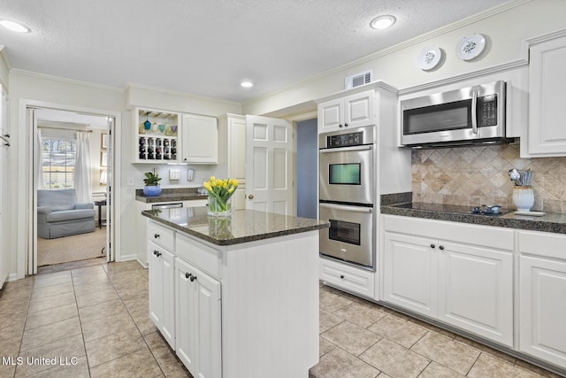 kitchen with stainless steel appliances, a kitchen island, and white cabinetry