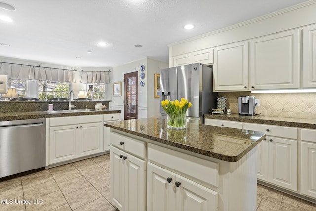 kitchen with stainless steel appliances, tasteful backsplash, light tile patterned flooring, white cabinetry, and a sink