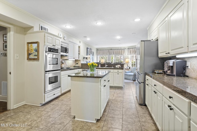 kitchen with stainless steel appliances, a peninsula, a kitchen island, visible vents, and tasteful backsplash