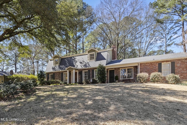 view of front of property with brick siding, a chimney, and a front lawn