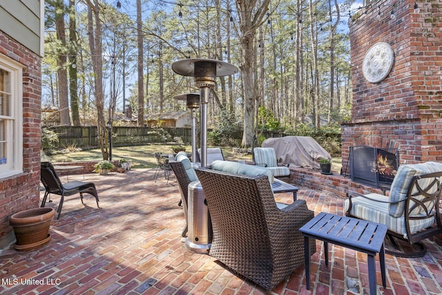 view of patio with an outdoor living space with a fireplace and fence