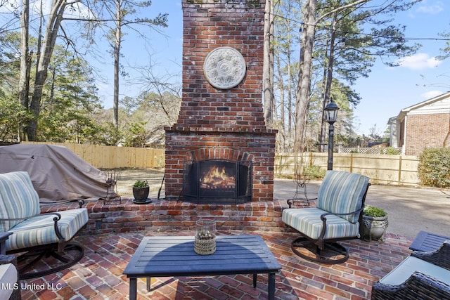 view of patio featuring an outdoor brick fireplace and fence