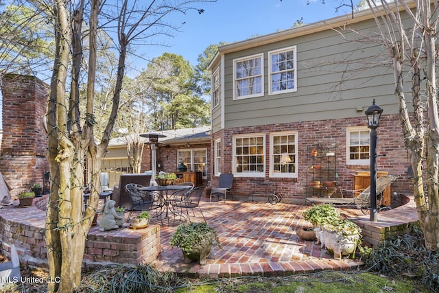 back of property with brick siding, outdoor dining area, and a patio area