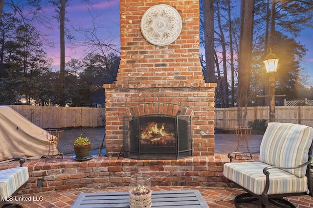 view of patio featuring an outdoor brick fireplace and fence