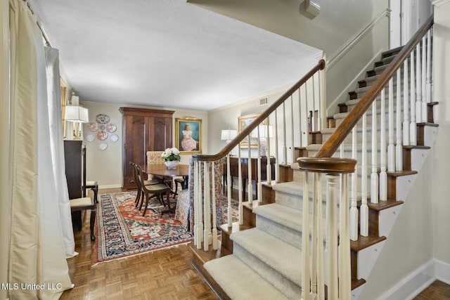 stairway with visible vents, baseboards, and ornamental molding