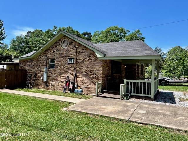 309 College St, Carthage, MS 39051 - view of side of home with a yard, brick siding, covered porch, and fence
