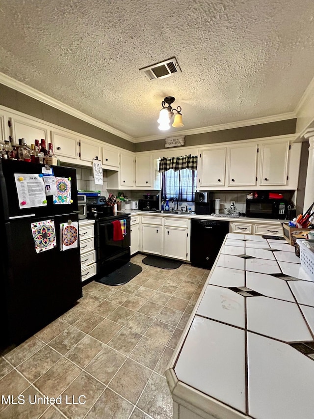 309 College St, Carthage, MS 39051 - kitchen with black appliances, ornamental molding, white cabinets, and visible vents