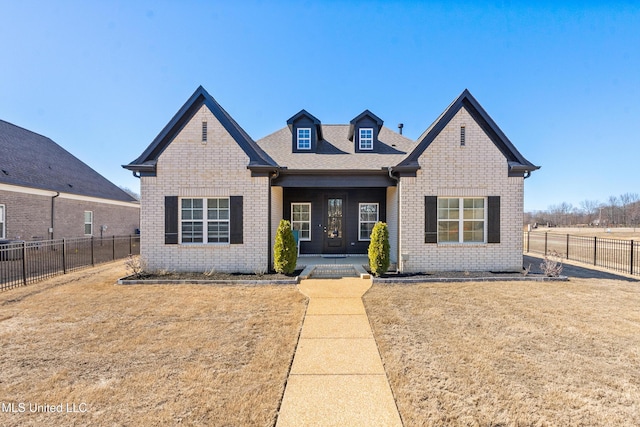 view of front facade with a front yard, brick siding, and fence