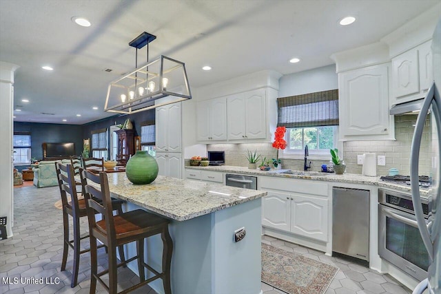 kitchen featuring a center island, white cabinets, decorative light fixtures, and stainless steel appliances