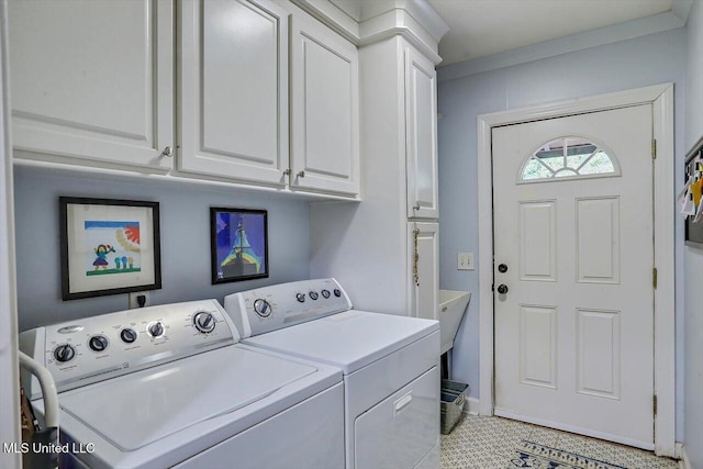 laundry room featuring crown molding, washing machine and clothes dryer, and cabinets