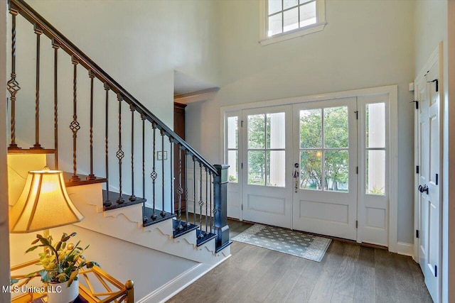 entrance foyer featuring a towering ceiling, dark wood-type flooring, and french doors