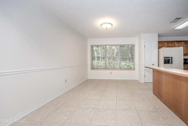 108 Water Oaks Cv, Ocean Springs, MS 39564 - kitchen featuring white fridge with ice dispenser, light countertops, a textured ceiling, light tile patterned flooring, and baseboards