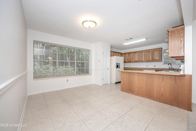 108 Water Oaks Cv, Ocean Springs, MS 39564 - kitchen featuring white fridge with ice dispenser, a peninsula, light countertops, a textured ceiling, and light tile patterned floors
