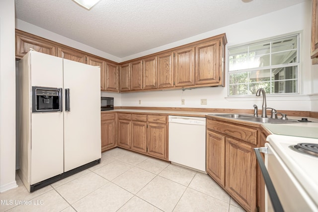 108 Water Oaks Cv, Ocean Springs, MS 39564 - kitchen featuring white appliances, a sink, brown cabinetry, a textured ceiling, and light tile patterned floors