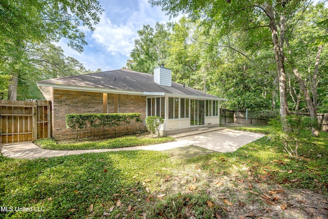108 Water Oaks Cv, Ocean Springs, MS 39564 - rear view of house featuring a sunroom, a chimney, brick siding, a patio area, and roof with shingles