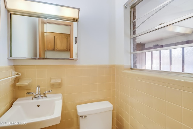 bathroom with sink, tile walls, and toilet