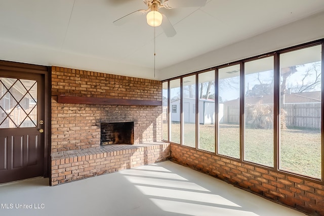 unfurnished sunroom featuring a brick fireplace and ceiling fan