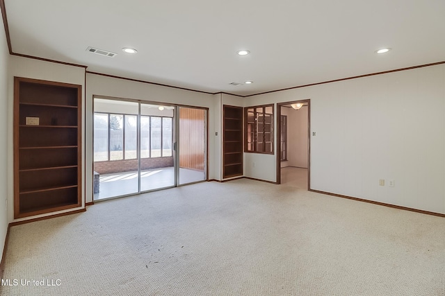 empty room featuring crown molding, light colored carpet, and built in shelves