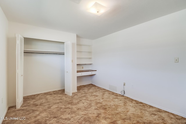 unfurnished bedroom with light colored carpet and a closet