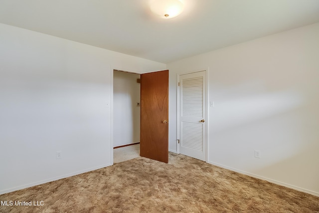 unfurnished bedroom featuring light colored carpet and a closet