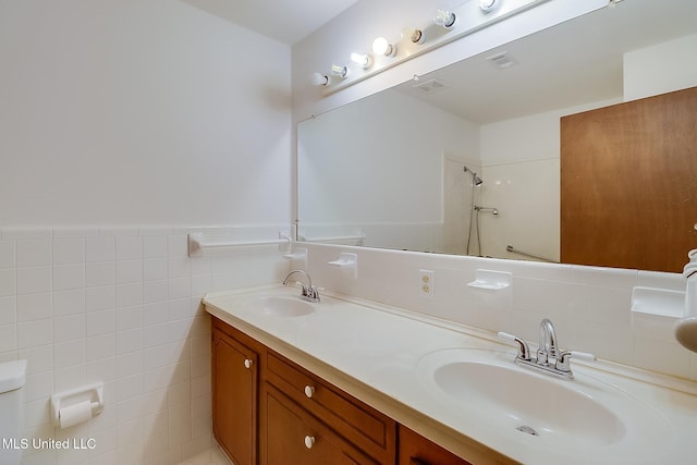 bathroom with vanity, tile walls, and a shower