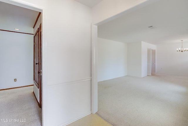 hallway with light colored carpet and a chandelier