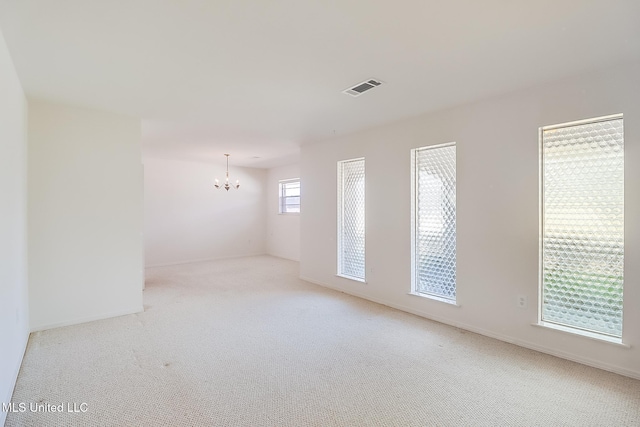 carpeted empty room featuring a chandelier